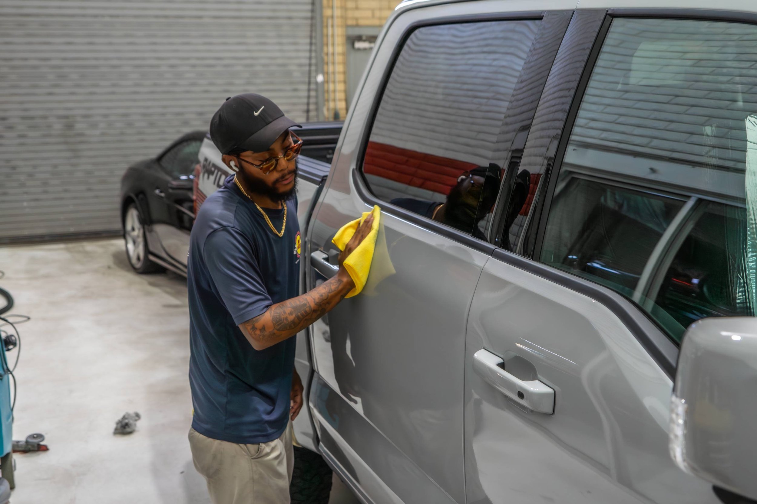 Detailer applying ceramic coating to a dark vehicle inside the Pit Stop Scottsdale shop